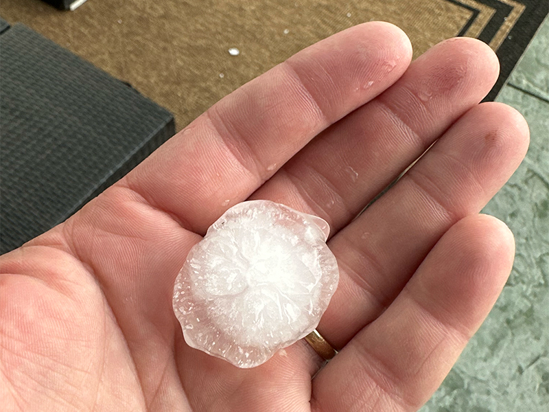 Large hailstone displayed on a person's hand